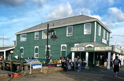 During the day people stand in front of the green and white building
